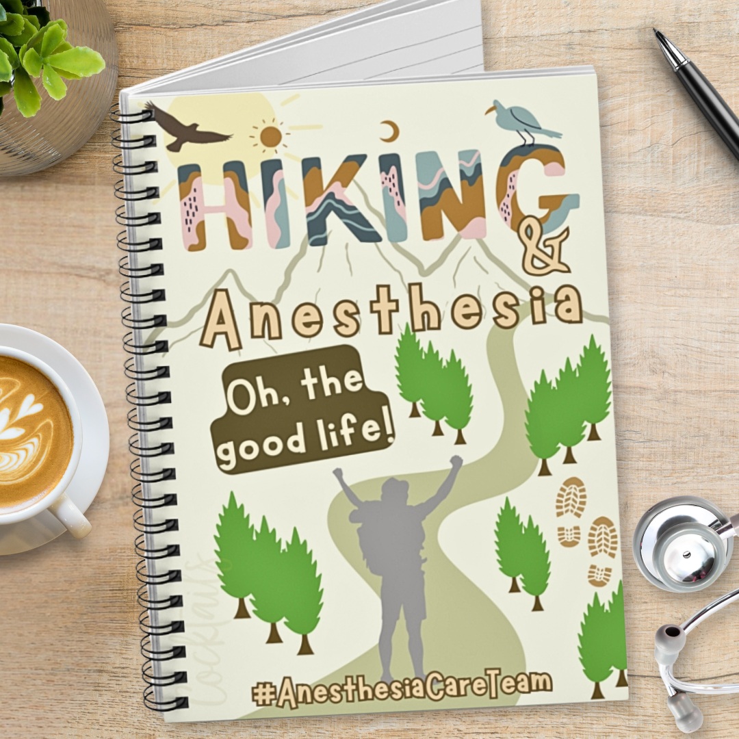 Notebook with hiking and anesthesia design and 'anesthesia care team' text on a wooden surface with coffee and stethoscope.