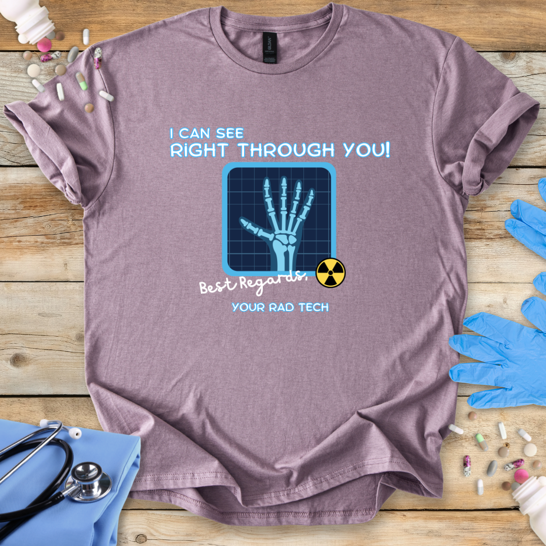 Pink t-shirt with medical radiology-themed graphic and 'I can see right through you' text on a wooden surface with medical gloves.