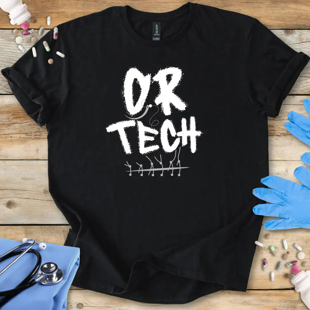 Black t-shirt with 'OR TECH' text on a wooden surface with medical supplies.