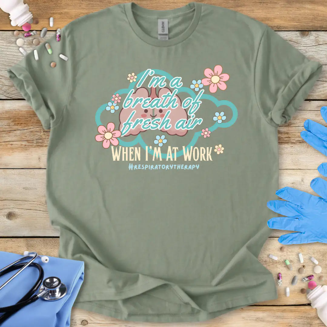 Sage Respiratory therapy themed T-shirt with a flower design and the text 'I'm a breath of fresh air, #respiratory therapy' on a wood background with medical supplies