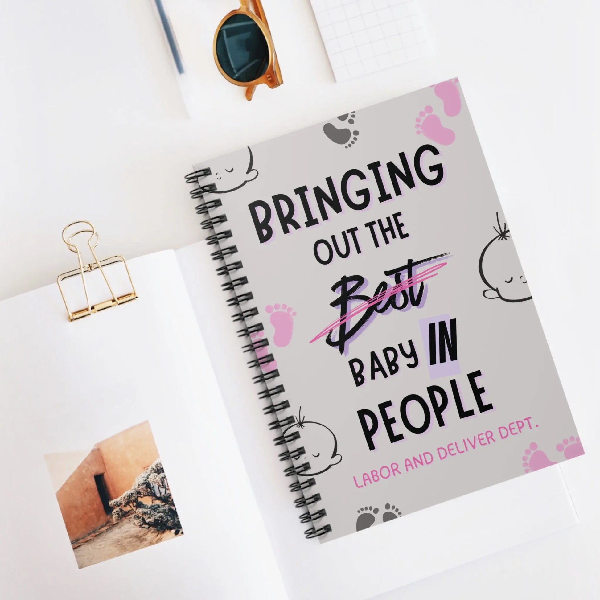 Obstetrics notebook with 'Bringing Out The Baby In People' quote on a desk