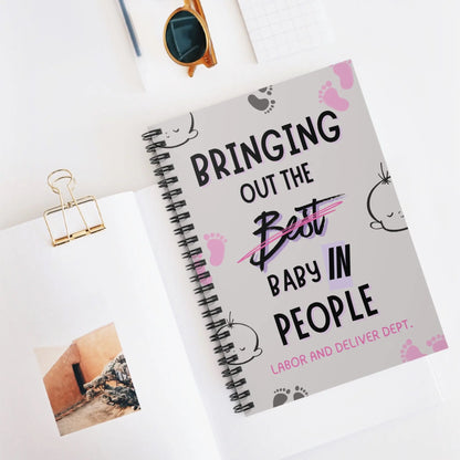 Obstetrics notebook with 'Bringing Out The Baby In People' quote on a desk