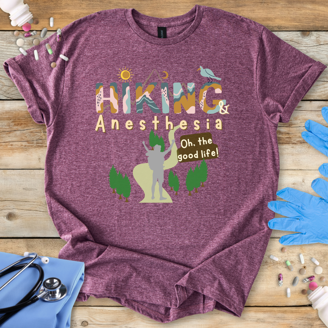 Maroon t-shirt with 'Hiking & Anesthesia' design on a wooden surface with medical supplies.