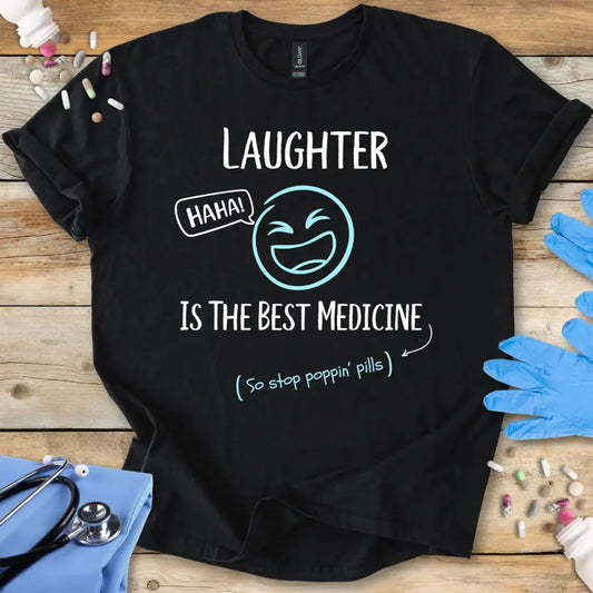 Black t-shirt with 'Laughter is the best medicine' text on a wooden surface with medical items.