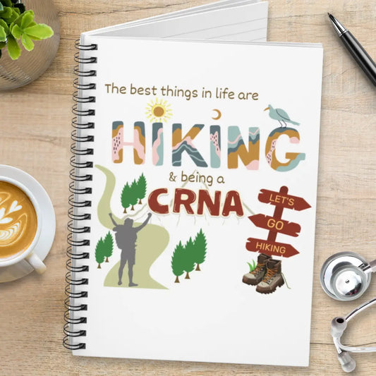 Spiral notebook with hiking-themed designs and 'The Best Things In Life Are Hiking & Being A CRNA' text on a wooden surface.