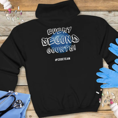 Black hoodie with 'Every Second Counts! #CODETEAM' text on a wooden surface with medical supplies.