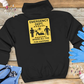Black hoodie back with yellow 'Emergency Dept. Where All the Fun Happens' warning sign graphic featuring patient injury icons, on a wooden background with stethoscope and medical gloves.