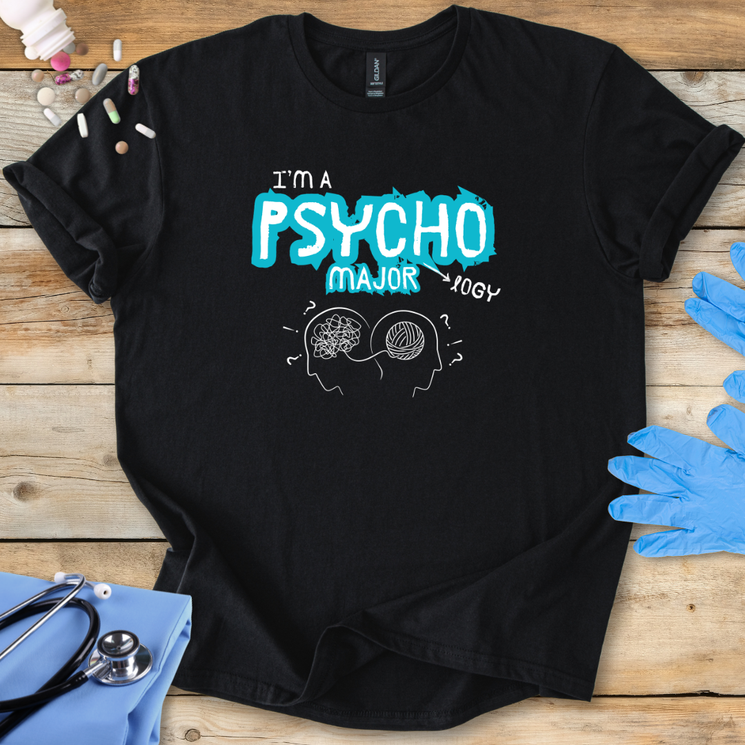 Black t-shirt with 'I'm a Psycho Major' design on a wooden surface with medical accessories.