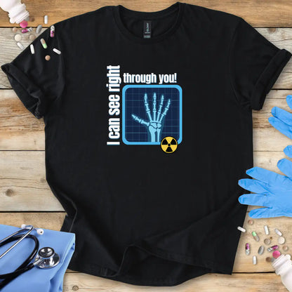 Black t-shirt with radiology humor text and X-ray graphic with 'I Can See Right Through You' text on a wooden surface with medical supplies.