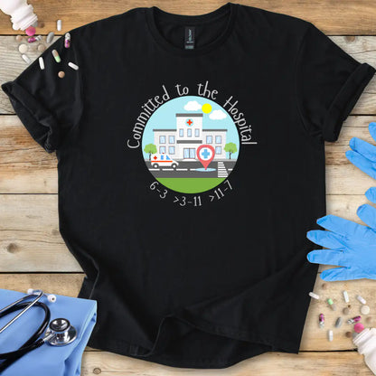 Black t-shirt with a hospital-themed graphic and 'Committed To The Hospital' on a wooden surface with medical supplies.