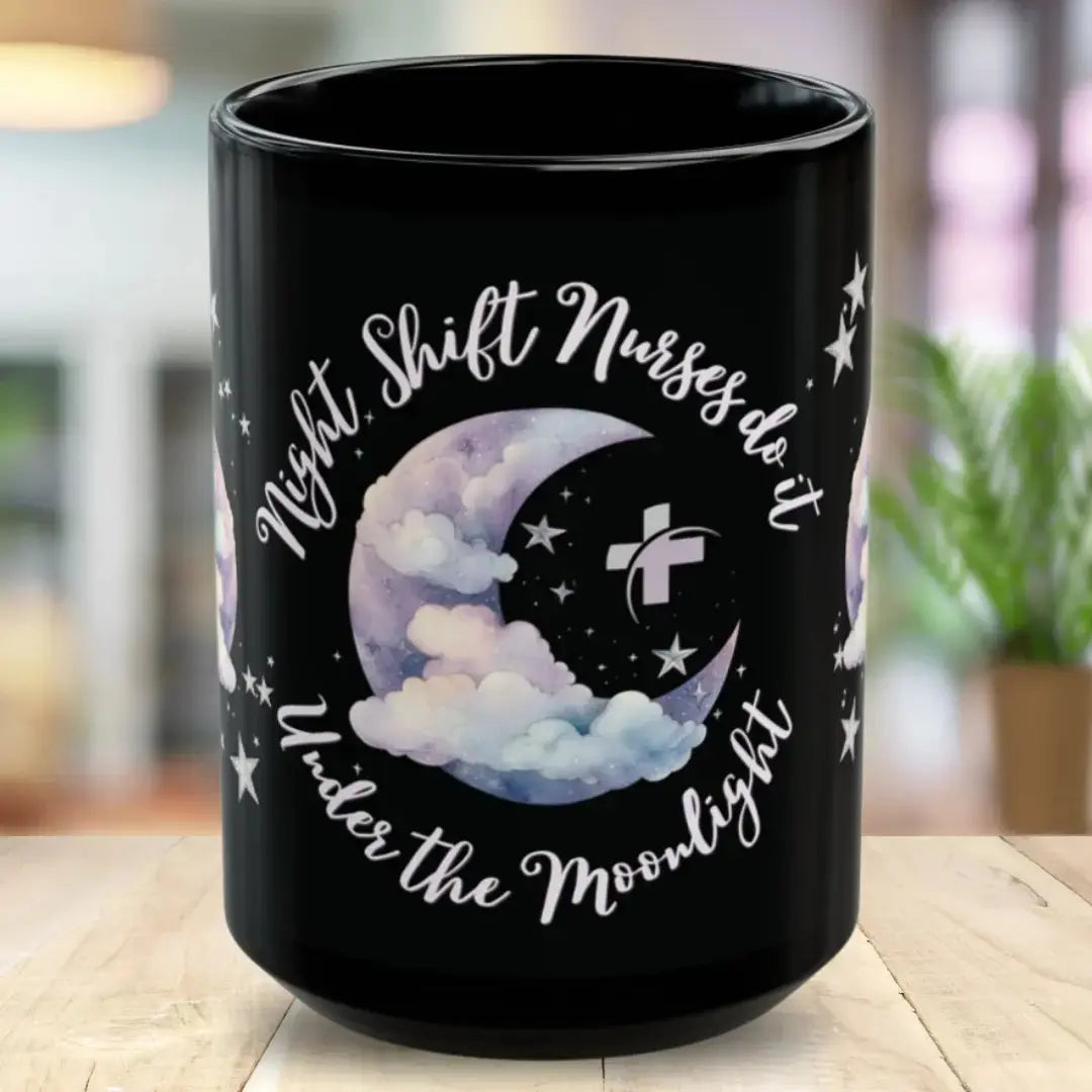 Black mug with moon and stars design and text 'Night Shift Nurses do it Under the Moonlight' on a blurred background.