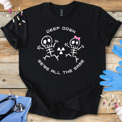 Black med t-shirt with radiology skeleton design and 'Deep down we are all the same' text on a wooden surface with medical supplies.