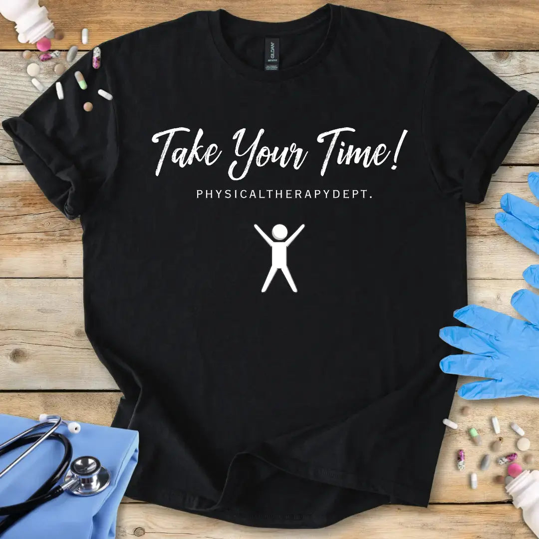 Black t-shirt with 'Take Your Time! Physical Therapy Dept.' text and graphic on a wooden surface with medical items.