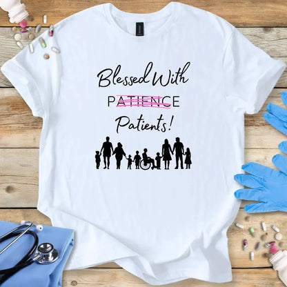 White med t-shirt with 'Blessed With Patients Not Patience!' text and family silhouette graphic on a wooden surface with medical items.