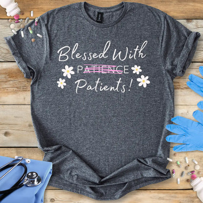Gray t-shirt with 'Blessed With Patients not Patience!' text on a wooden surface with medical accessories.