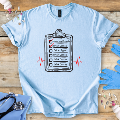 Light blue t-shirt with a medical-themed graphic on a wooden surface with medical accessories.