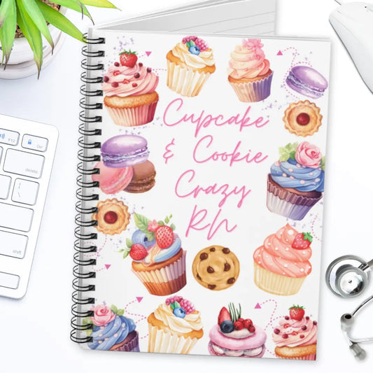 Notebook with 'cupcake and cookie crazy rn' text design on a white surface with a keyboard.