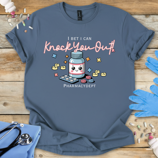 Indigo Blue med t-shirt with a pharmacy-themed graphic and 'I bet I can knock you out' text on a wooden surface with medical accessories.