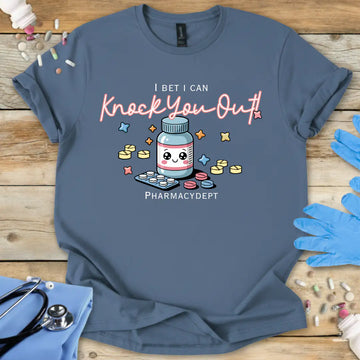 Indigo Blue med t-shirt with a pharmacy-themed graphic and 'I bet I can knock you out' text on a wooden surface with medical accessories.