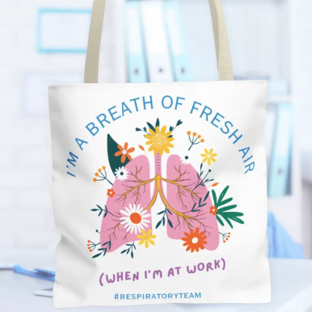 Tote bag with lungs and flowers design and text 'I'm a breath of fresh air (when I'm at work) #Respiratory Team' on a blurred medical background.