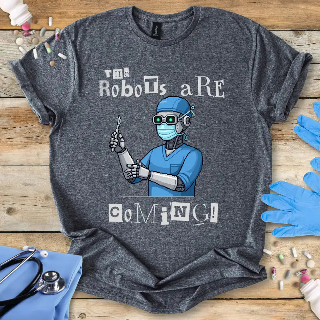 Gray t-shirt with a robot in scrubs graphic and text 'The robots are coming' on a wooden surface with medical accessories.