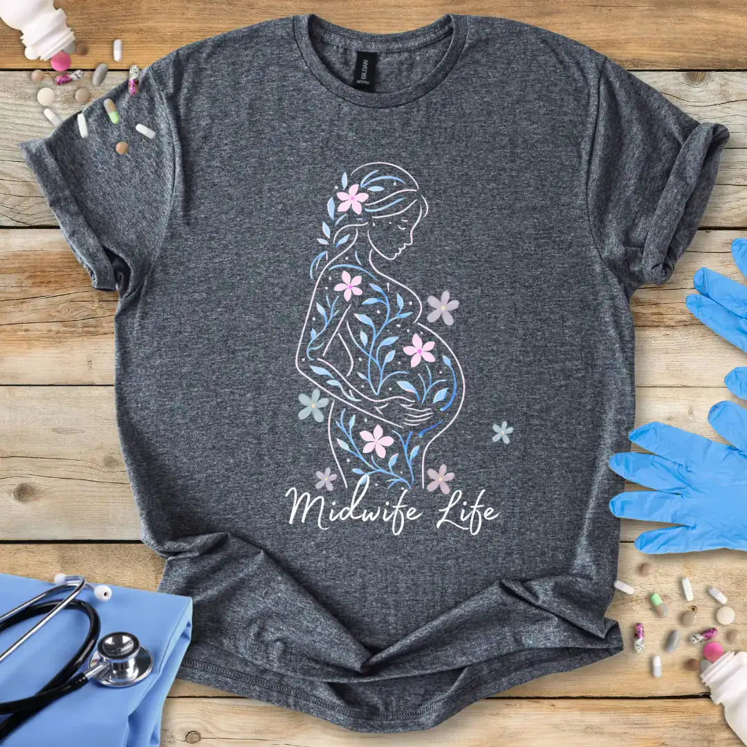 Dark-Heather t-shirt with a pregnant silhouette and 'Midwife Life' text on a wooden surface with medical accessories.