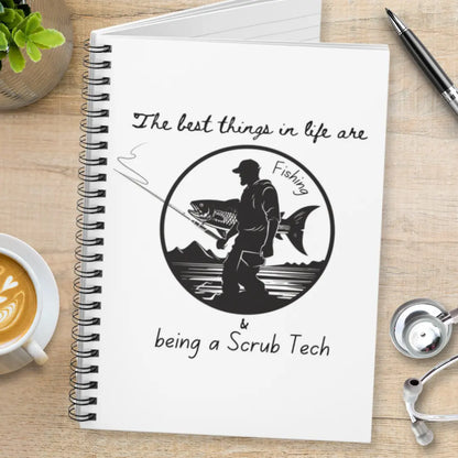 Notebook with fishing illustration and 'The Best Things In Life Are Fishing And Being a Scrub Tech' text on a wooden table.