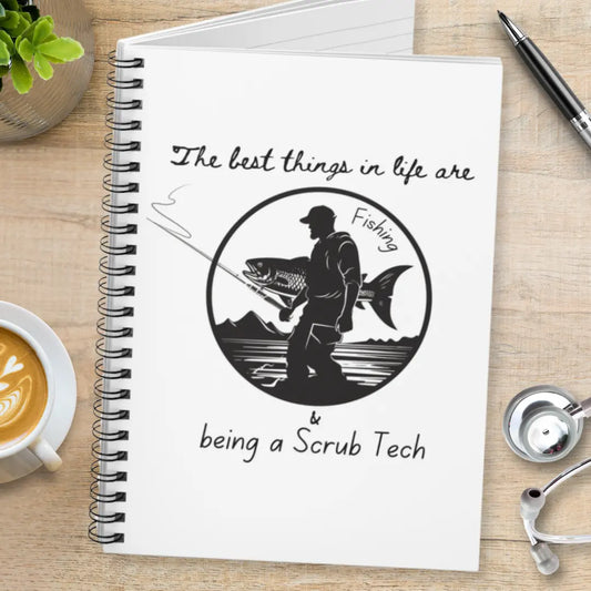 Notebook with fishing illustration and 'The Best Things In Life Are Fishing And Being a Scrub Tech' text on a wooden table.