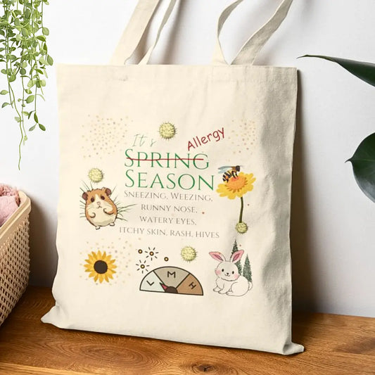 Funny tote bag with allergy season themed illustrations and 'It's Allergy Season' text on a wooden surface.