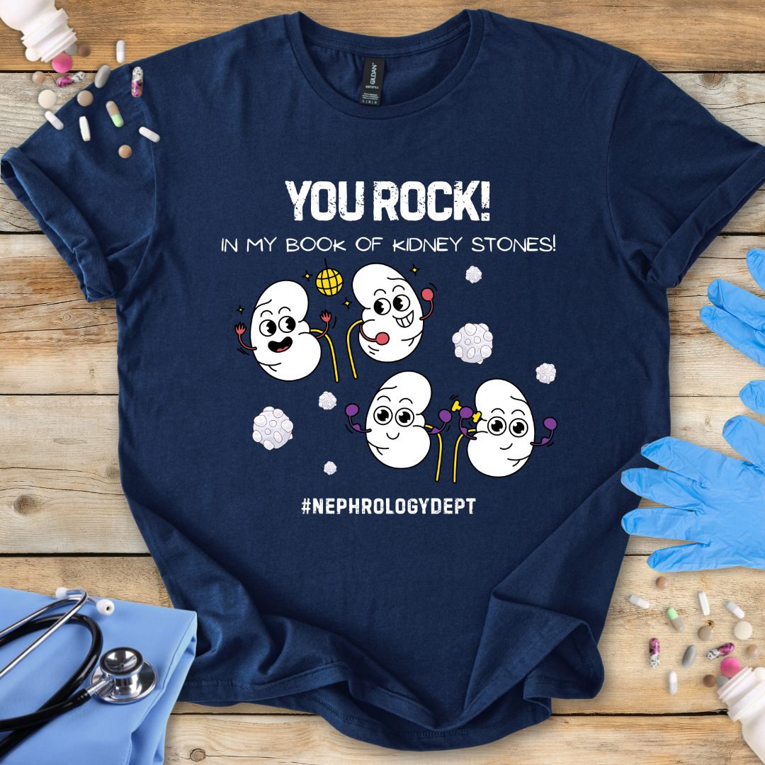 Navy t-shirt with cartoon kidneys and 'You rock in my book of kidney stones, nephrology dept.' text on a wooden surface with medical accessories.