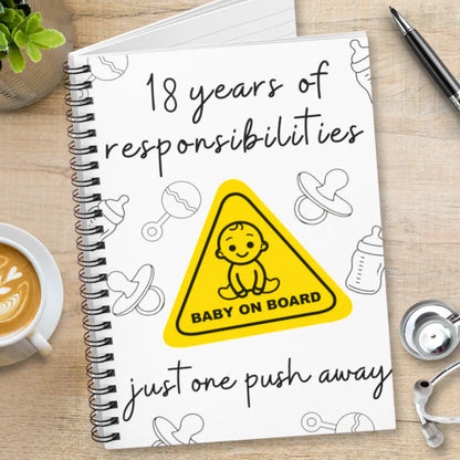 Labor and delivery notebook with '18 years of responsibilities' and 'Baby on Board' logo on a wooden surface.