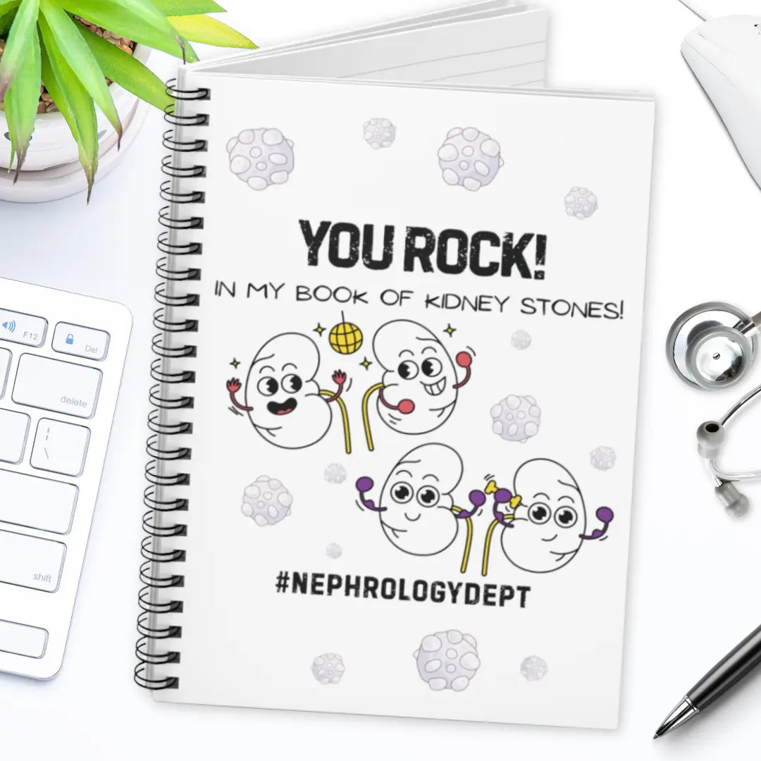 Nephrology notebook with cartoon kidneys and 'You Rock In My Book Of Kidney Stones' text on a desk.