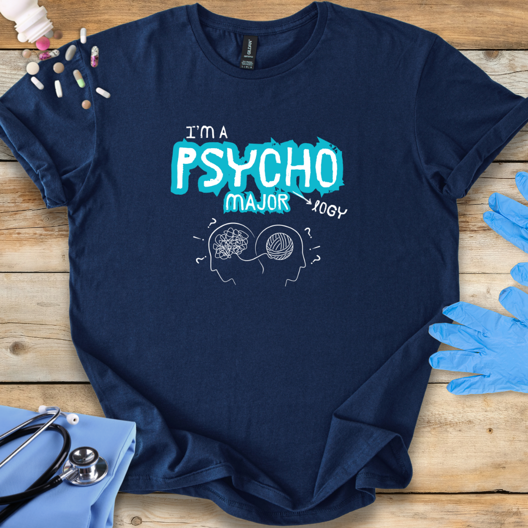 Navy blue t-shirt with 'I'm a Psycho Major' design on a wooden surface with medical accessories.