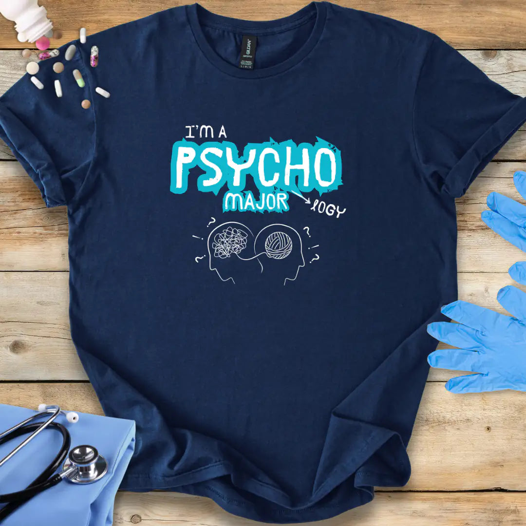Navy blue t-shirt with 'I'm a Psycho Major' design on a wooden surface with medical accessories.