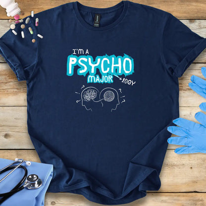Navy blue t-shirt with 'I'm a Psycho Major' design on a wooden surface with medical accessories.
