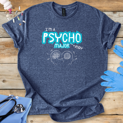 Blue t-shirt with 'I'm a Psycho Major' design on a wooden surface with gloves and stethoscope.