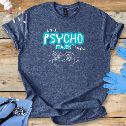Blue t-shirt with 'I'm a Psycho Major' design on a wooden surface with gloves and stethoscope.