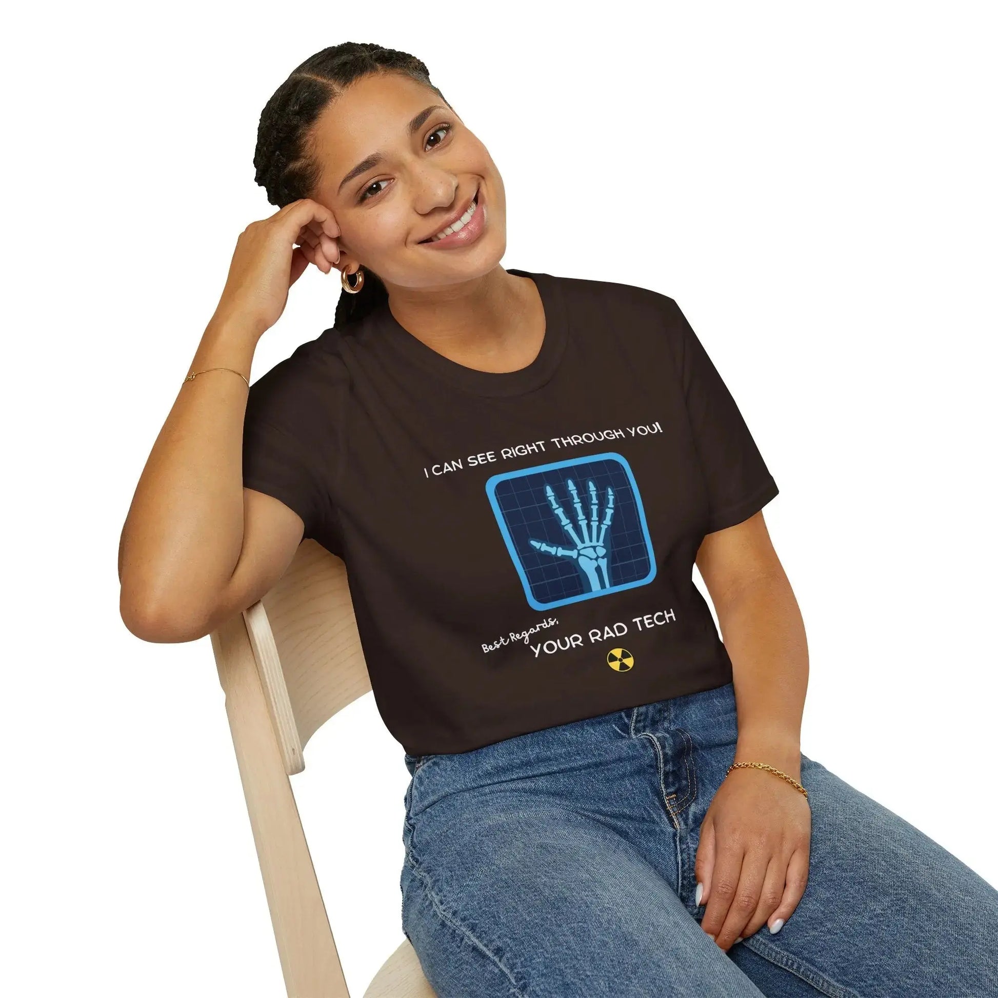 Person wearing a brown t-shirt with a graphic and 'I Can See Right Through You' text, sitting on a chair.
