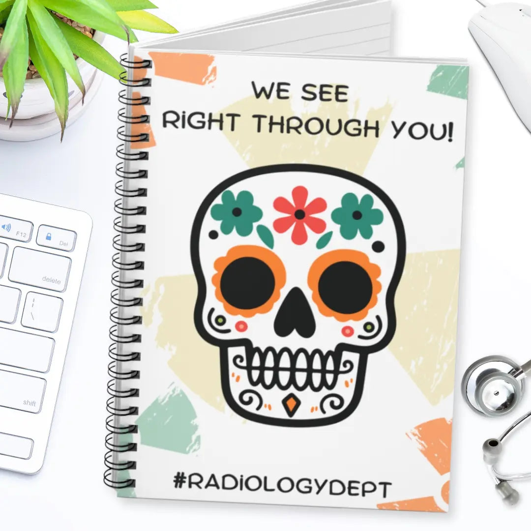 Radiology notebook with a colorful skull design and 'We See Right Through You' text on a desk with medical equipment.