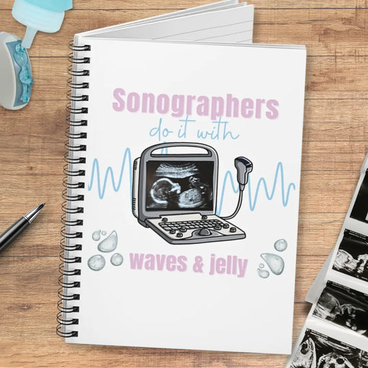 Notebook with sonography-themed design and 'Sonographers Do It With Waves & Jelly' text on a wooden surface.