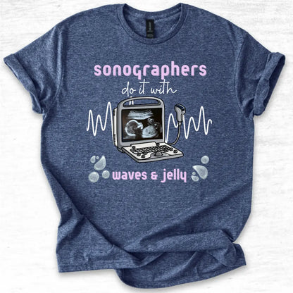 Blue t-shirt with ultrasound graphic and text 'Sonographers do it with waves & jelly' on a light gray background