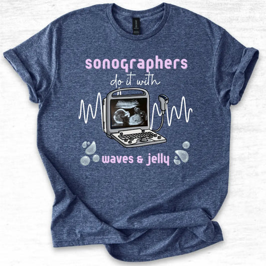 Blue t-shirt with ultrasound graphic and text 'Sonographers do it with waves & jelly' on a light gray background