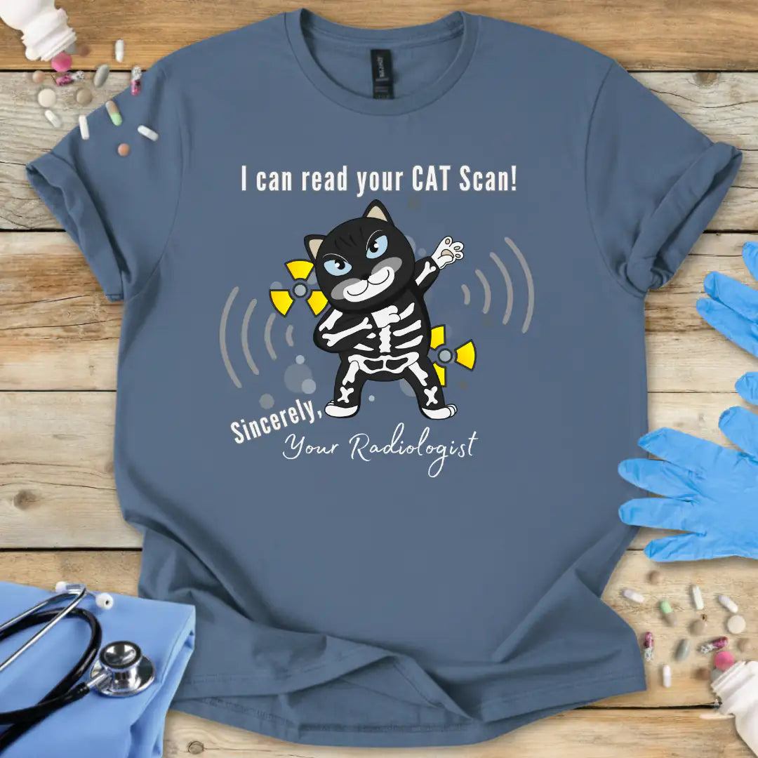 Indigo blue t-shirt with cartoon cat in an x-ray and 'I can read your cat scan your radiologist' text on a wooden surface with medical-themed props.