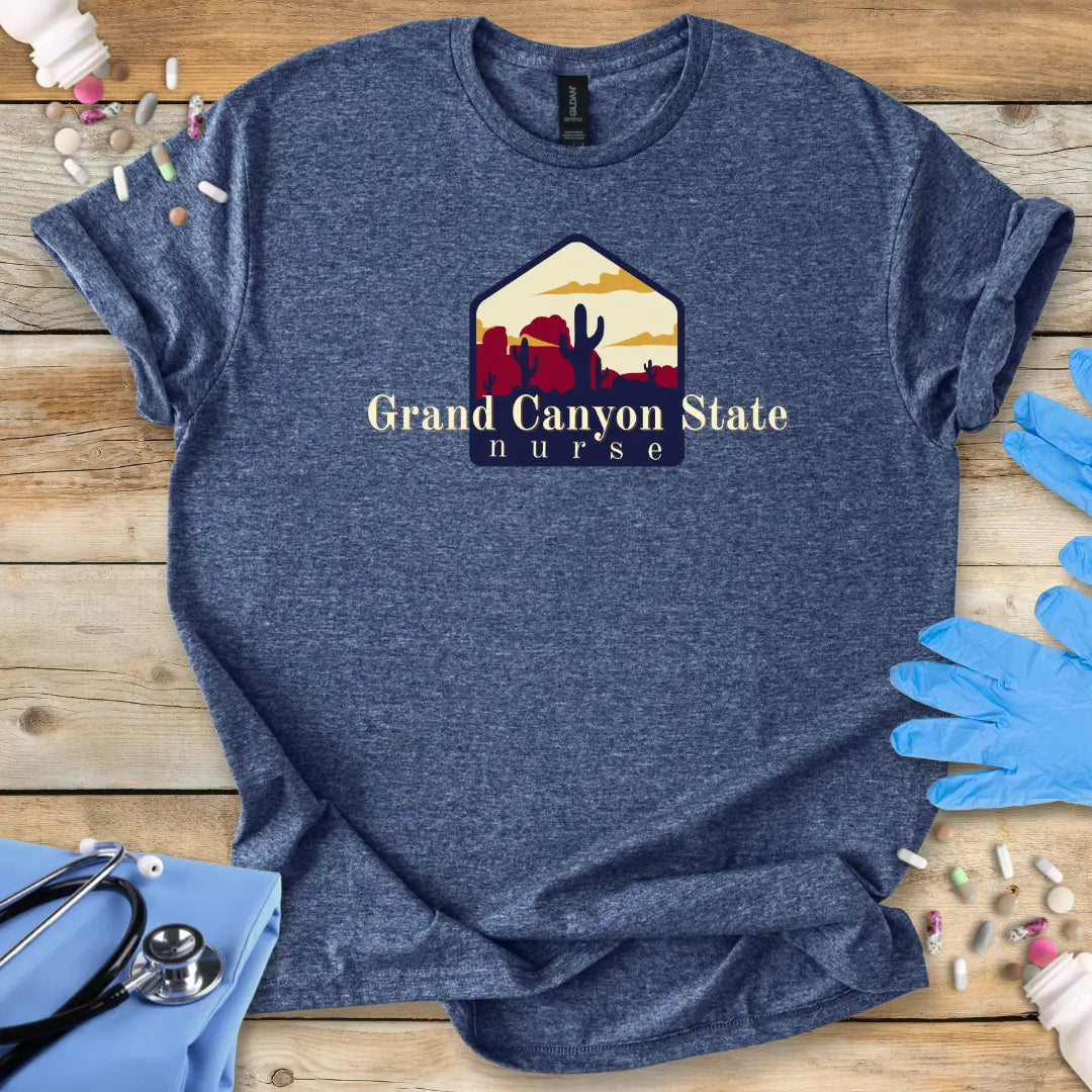 Blue t-shirt with 'Grand Canyon State Nurse' design on a wooden surface with medical supplies.