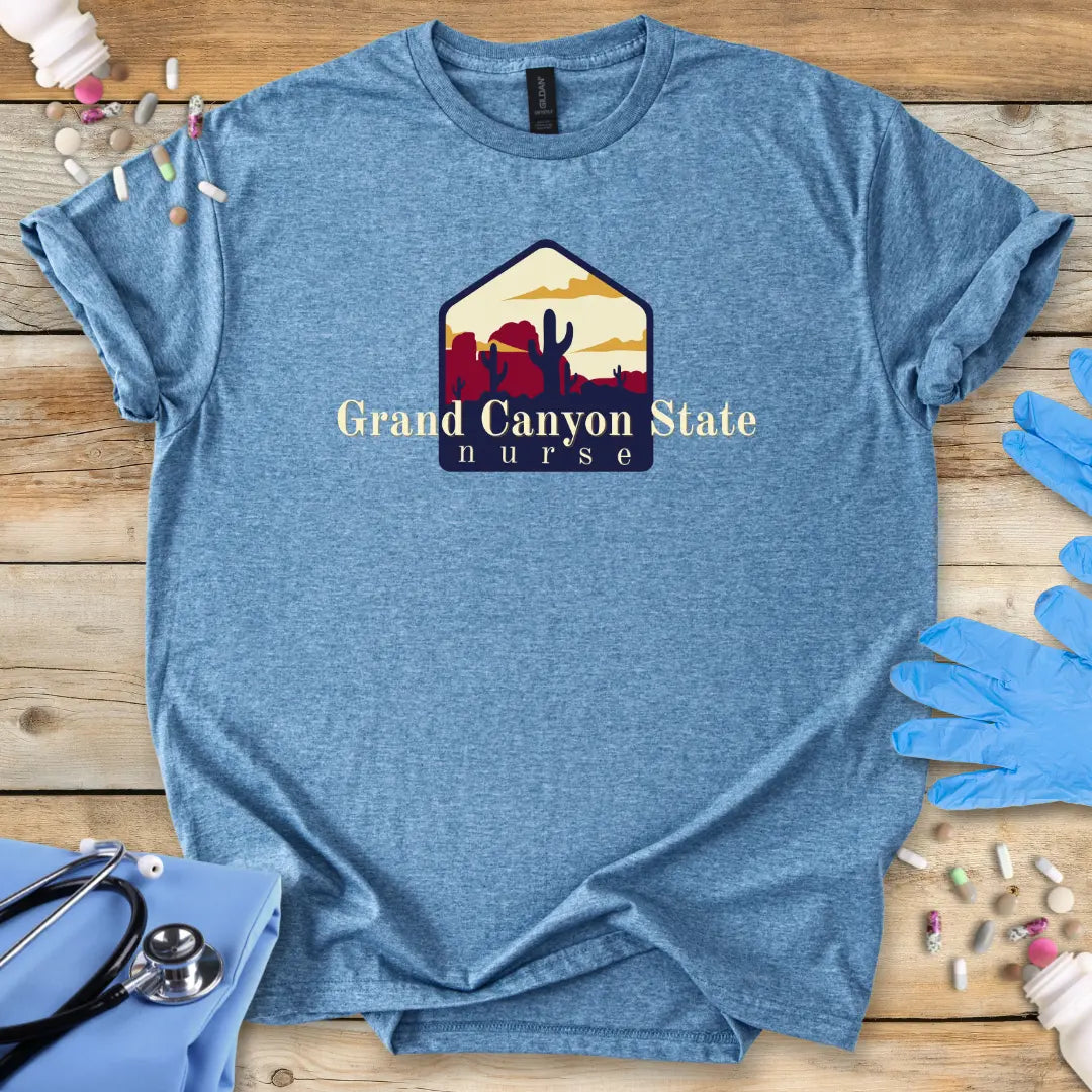 Blue t-shirt with 'Grand Canyon State Nurse' design on a wooden surface with gloves and medical supplies.