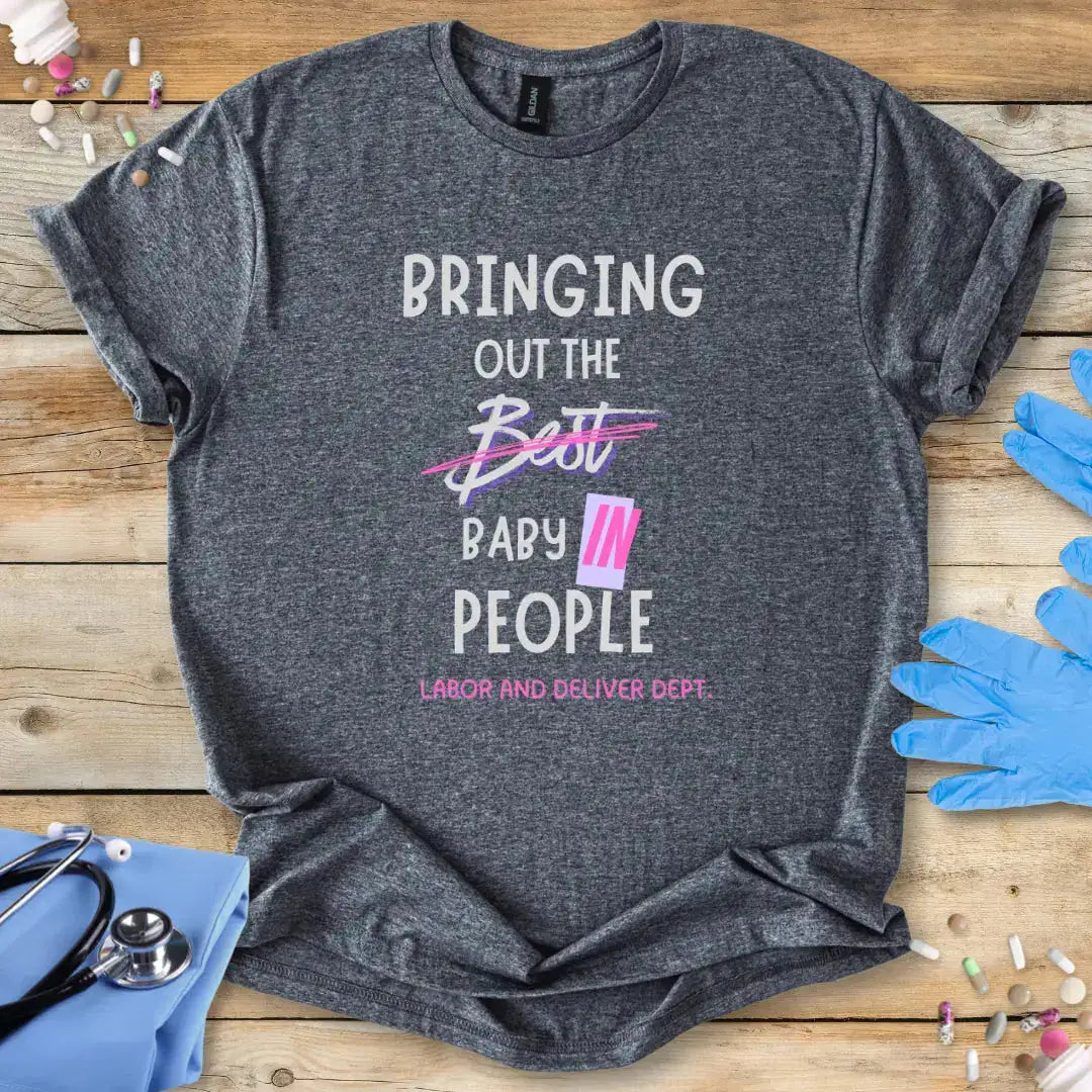 Gray med t-shirt with humorous text design on a wooden surface with medical-themed items.