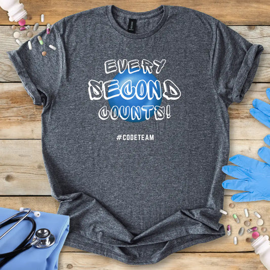 Gray t-shirt with 'Every Second Counts! Code Teams' print on a wooden surface with medical supplies.