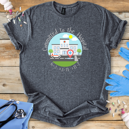 Gray t-shirt with a hospital-themed graphic and 'Committed To The Hospital' on a wooden surface with medical supplies.