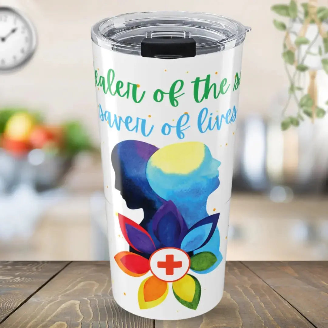 Stainless steel tumbler with colorful medical design and 'Healer Of The Sick Saver Of Lives' text on a wooden surface