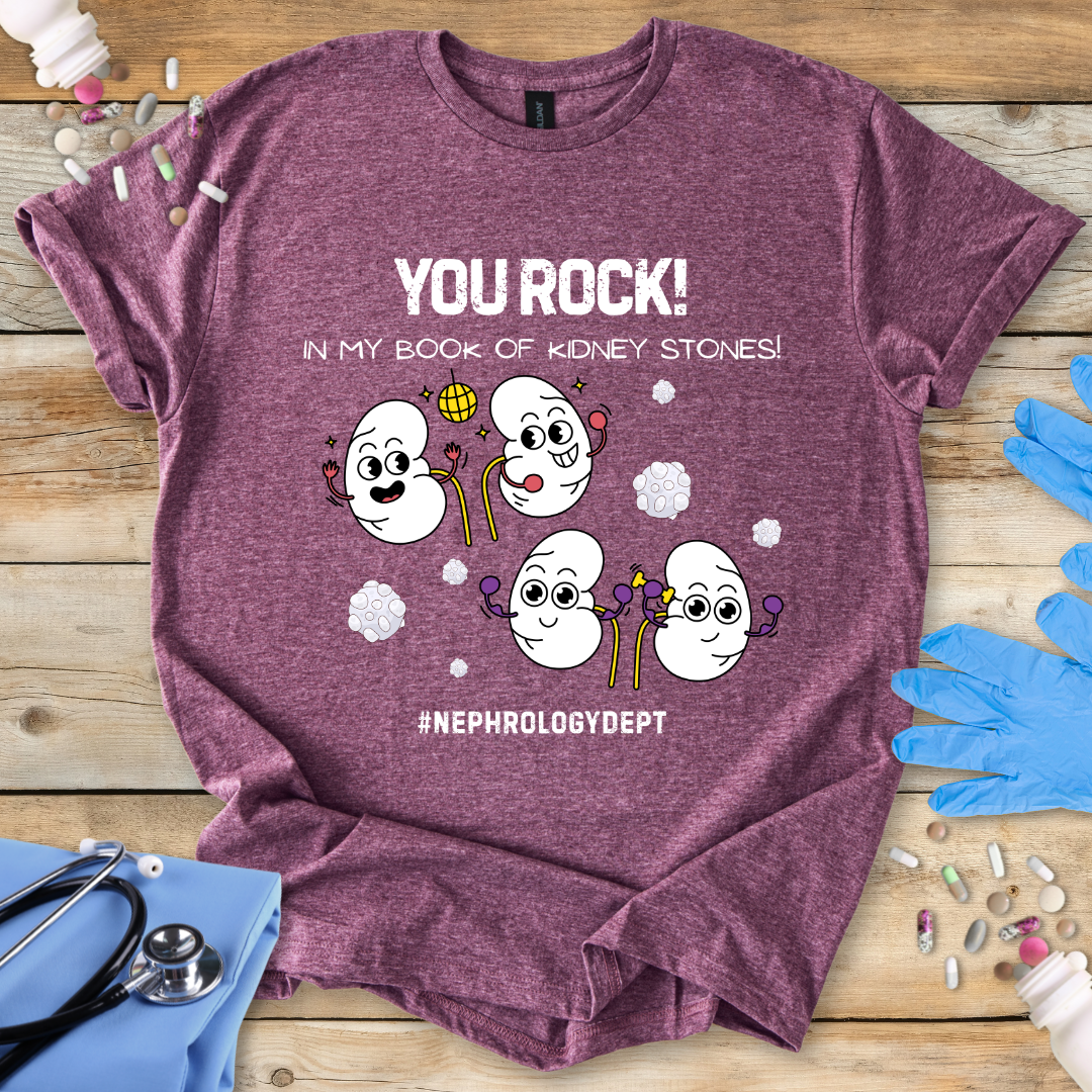 Heather Maroon gildan t-shirt with cartoon kidneys and 'You rock in my book of kidney stones, nephrology dept.' text on a wooden surface with medical accessories.